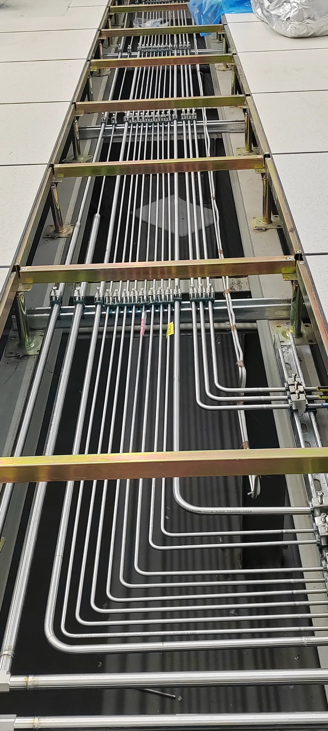 Supported stainless-steel laboratory gas lines routed beneath an access floor