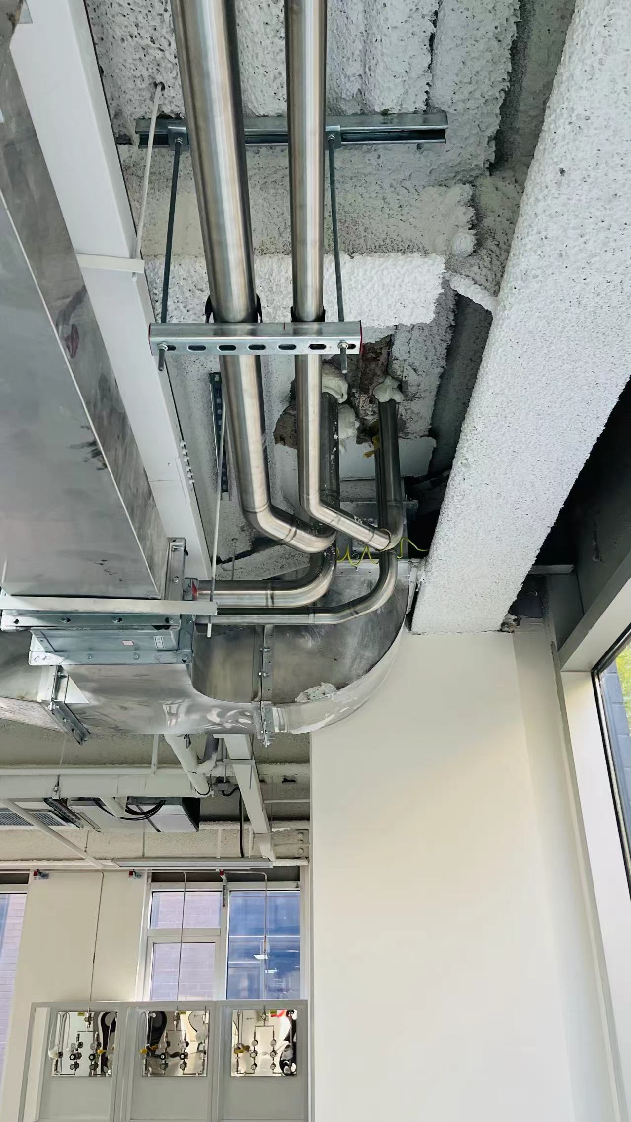 Stainless service pipes routed above a laboratory ceiling during construction