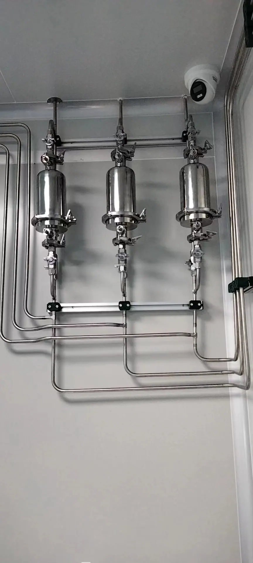 Stainless-steel gas piping and compact equipment mounted along a laboratory wall